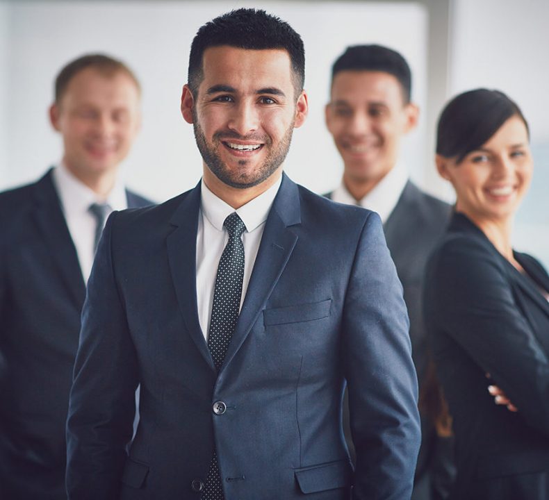 Portrait of confident business partners looking at camera with smiling leader in front